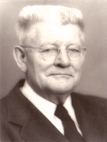 Portrait of Theodore Sigvaard Mondale. Theodore has white hair and glasses and is wearing a suit..