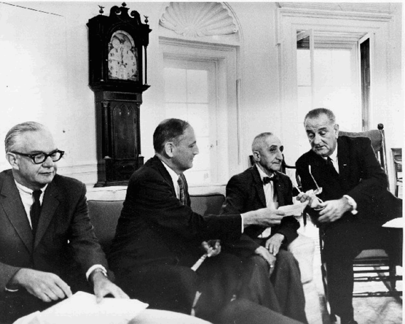 President Lyndon Johnson, Secretary of HEW John Gardner, and SSA Commissioner Bob Ball received the first Medicare Part-B application form from a member of the general public, Mr. Tony Palcaorolla, 1965