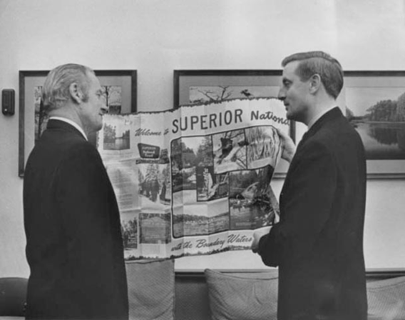 Senator Mondale and another gentleman looking at an unfolded visitor guide of the Superior National Park