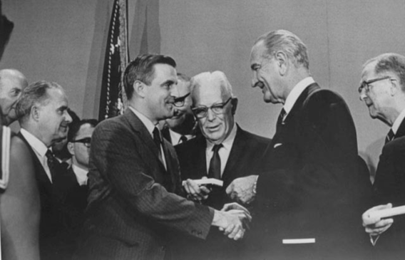 Walter Mondale shaking hands with President Johnson. 